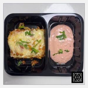 Lazanija su jautiena, gardinta paprikomis ir pomidorais, užkepta kietuoju sūriu, pateikiama su pikantišku padažu