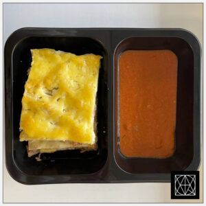 Lazanija su vištiena, gardinta paprikomis ir pomidorais, užkepta kietuoju sūriu, pateikiama su pikantišku padažu