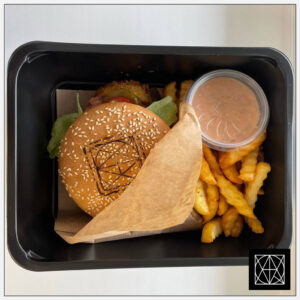 Mėsainis su gruzdinta vištienos krūtinėle, šonine, pomidorais, salotomis, svogūnais, čederiu, česnakiniu majonezo-teriyaki padažu ir gruzdintomis bulvytėmis