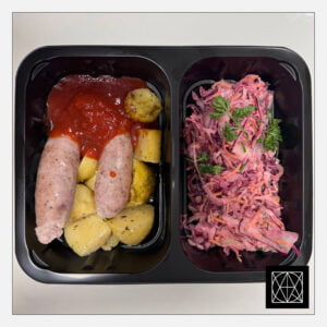 Naminės kiaulienos dešrelės su pomidorų padažu, pateikiamos su keptomis bulvėmis, gardintomis kmynais ir „Coleslaw“ salotomis