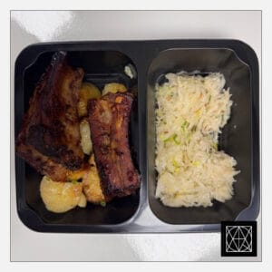 Ilgo kepimo kiaulienos BBQ šonkauliai, pateikiami su keptomis bulvėmis ir mūsų raugintais kopūstais, gardintais aliejumi ir svogūnėliais