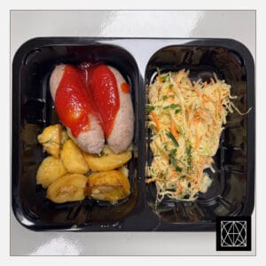 Naminės kiaulienos dešrelės su pomidorų padažu, pateikiamos su keptomis bulvėmis ir kopūstų salotomis, gardintomis majonezu