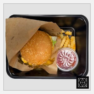 Mėsainis su plėšyta BBQ kiauliena, marinuotais agurkais, pomidorais, čederio sūriu, česnakiniu majonezo-teriyaki padažu ir gruzdintomis bulvytėmis