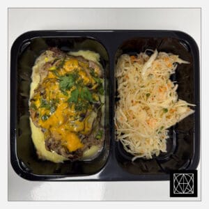 Kiaulienos kepsnys, užkeptas grybais ir čederio sūriu, pateikiamas su sviestine bulvių koše ir šviežių kopūstų salotomis, gardintomis krapais